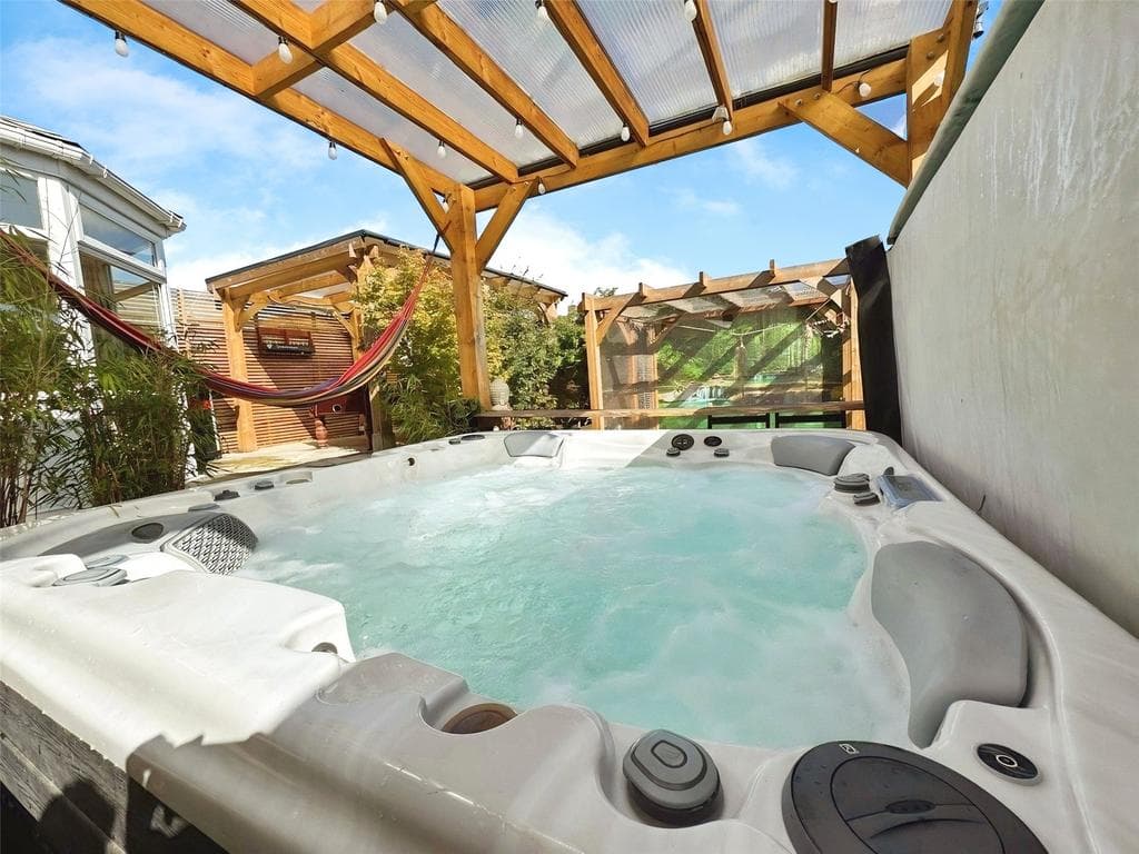 Wellis hot tub under the cedar pergola at dusk